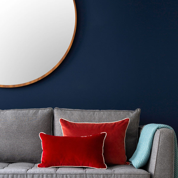 Canapé gris avec coussin rouge avec mur bleu